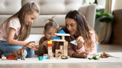 
		Young woman playing with two children on the floor
	